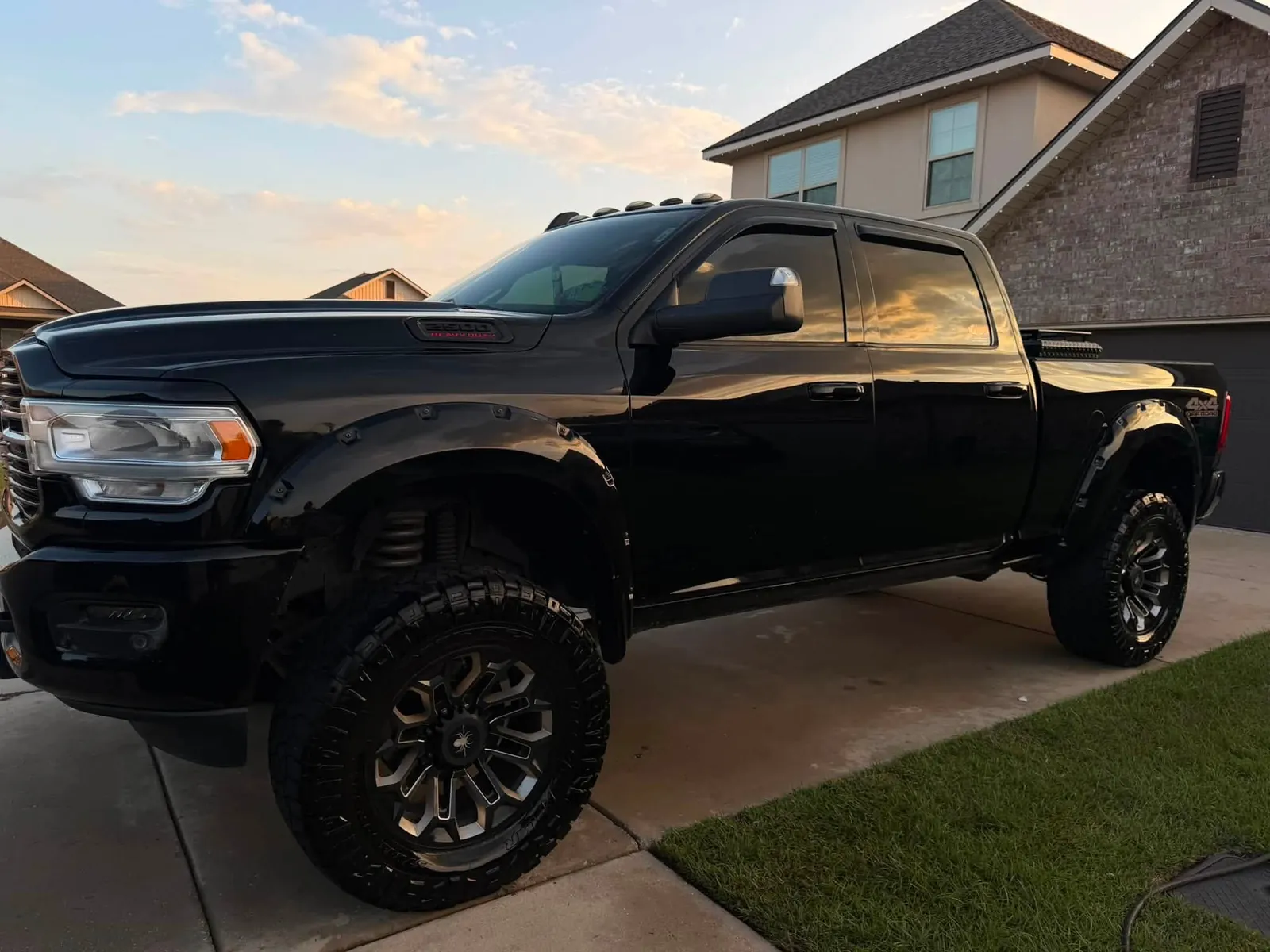 Lifted black pickup truck in a driveway at golden hour after an exterior detail